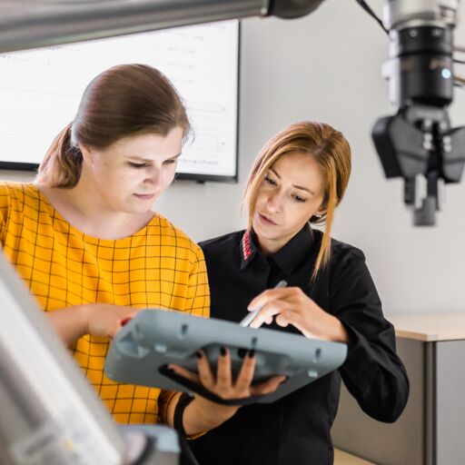 Eine Trainerin zeigt einer Mitarbeiterin etwas auf einem Tablet zur Steuerung eines Robotors in der Rotax Academy